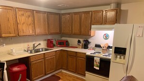 A kitchen with wooden cabinets, a stainless steel sink, a red coffee maker, a microwave, and a refrigerator. - Lovelock Pet-Friendly Studio Next to I-80 (Lovelock)
