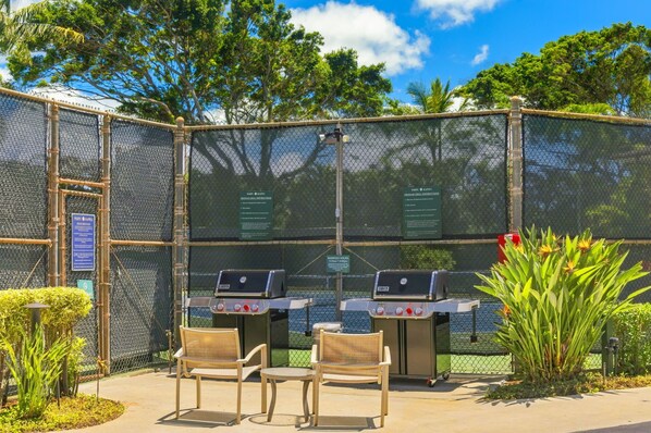 A fenced outdoor area with barbecue grills and seating.