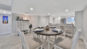 Een eetgedeelte met een ronde tafel voor vier personen, omringd door witte stoelen met een zittingkussen.
