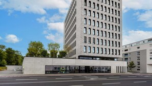 Un edificio moderno con techo plano, múltiples ventanas y un amplio espacio de entrada.