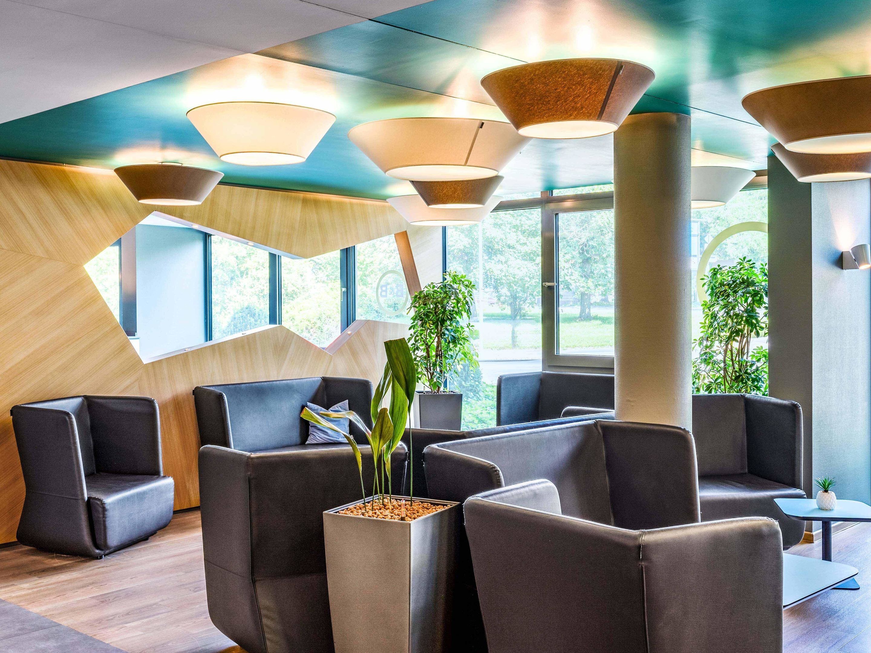 A modern waiting area with cushioned seating, large windows, and contemporary lighting fixtures.