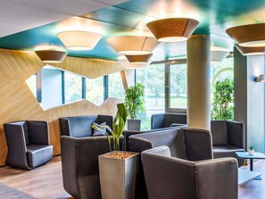 Un espace d’attente moderne doté de sièges rembourrés, de grandes fenêtres et d’un éclairage contemporain.