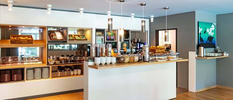 Una barra de desayuno moderna con diversos alimentos y una máquina de café.