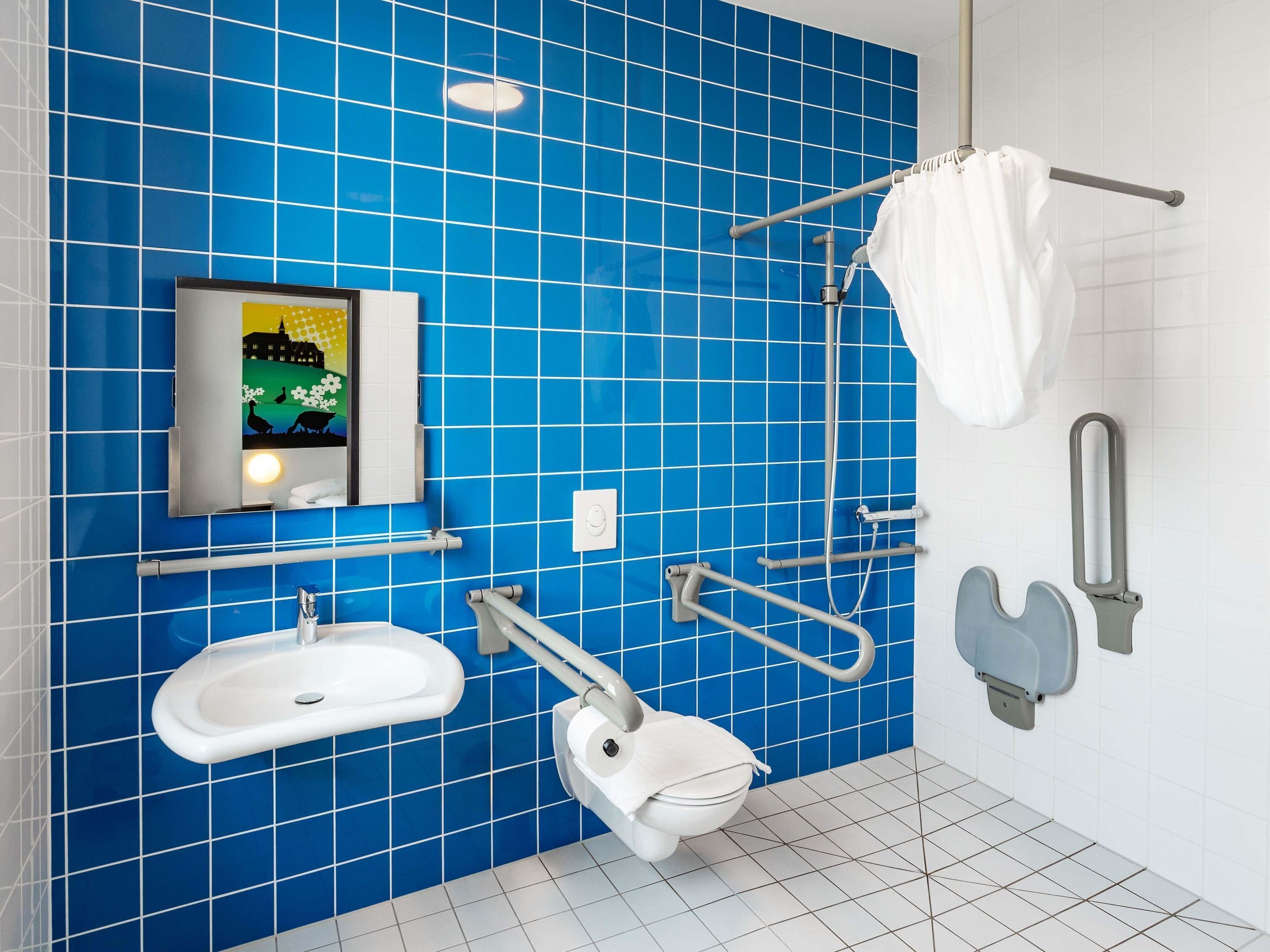 Un baño con azulejos azules, un lavabo, un inodoro y una zona de ducha.
