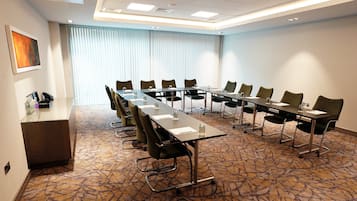 A conference room with a long table, chairs, and a carpeted floor.