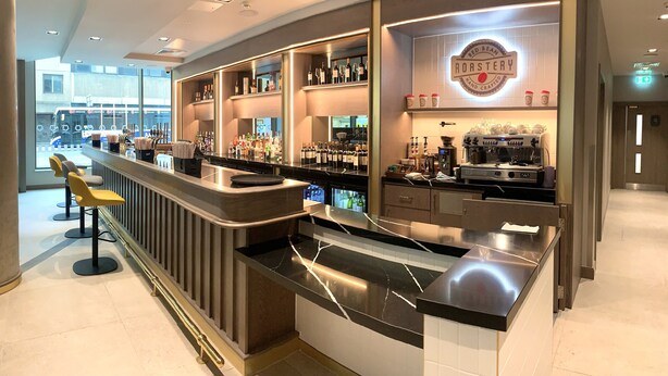 A modern bar area with a counter, stools, and shelves stocked with bottles. - Maldron Hotel Glasgow City (Glasgow)