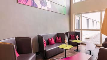 Un espace de détente moderne avec des canapés en cuir, des coussins rouges et de petites tables.