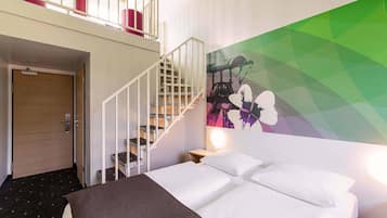 Une chambre d’hôtel avec un lit, un escalier, une fresque murale et un balcon agrémenté de coussins rouges.
