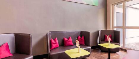 A modern lobby with leather sofas, yellow tables, and a large abstract painting on the wall.