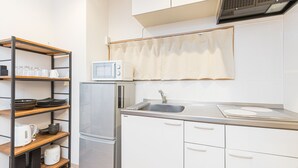 A compact kitchen with a microwave, refrigerator, and a sink. - Mita Guest House (Tokyo)