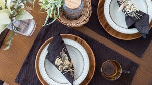 A table set with white plates, dark napkins, and a glass of amber liquid, likely tea or coffee. - Mita Guest House (Tokyo)