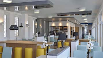 A modern hotel lobby with a central bar area, seating arrangements, and a reception desk.