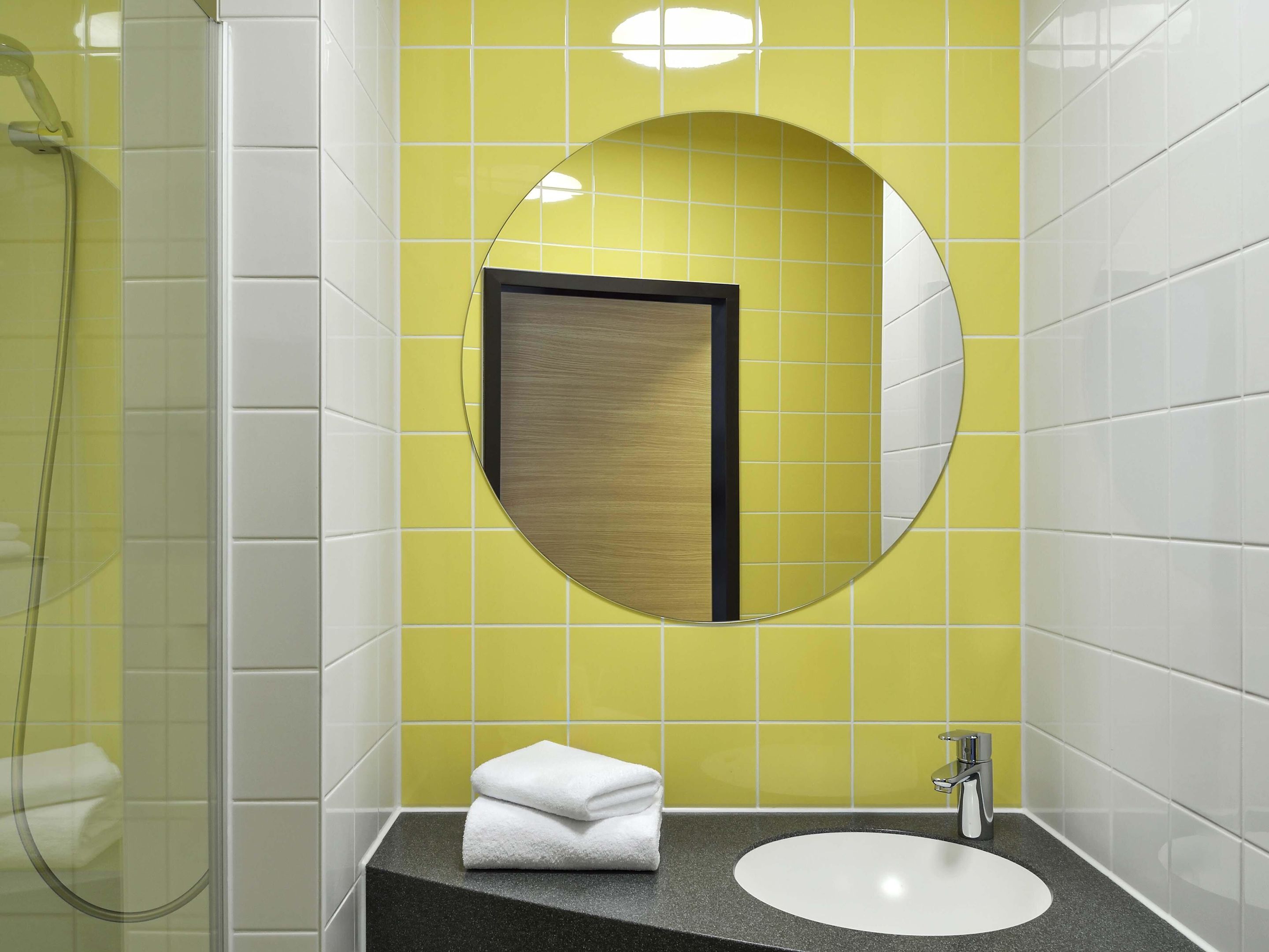 Un baño con un espejo redondo, un lavabo y una ducha.