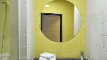 Un baño con un espejo redondo, un lavabo y una ducha.