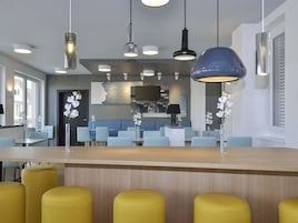 Un interior de restaurante moderno con una zona de bar, disposición de mesas y elementos decorativos como orquídeas.