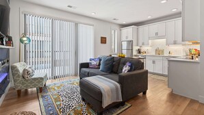 A modern living room with a sofa, ottoman, and a patterned rug.