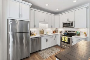 Une cuisine moderne avec des meubles blancs, des appareils en acier inoxydable et un plancher en bois.