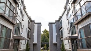 A modern apartment building with a central courtyard, balconies, and a well-maintained lawn.