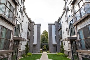 A modern apartment building with a central courtyard, balconies, and a brick facade.