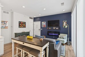Un salon moderne comprenant une table à manger, un canapé, un téléviseur et des œuvres d’art accrochées aux murs.