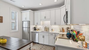 A modern kitchen with white cabinets, stainless steel appliances, and a tiled backsplash.
