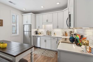 A modern kitchen with white cabinets, a stainless steel refrigerator, and a white countertop.