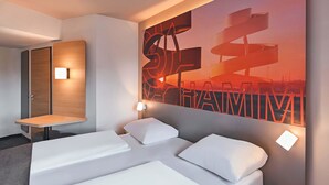 A modern hotel room with a large bed, a desk, and a wall-mounted artwork. - B&B Hotel Hamm (Hamm)