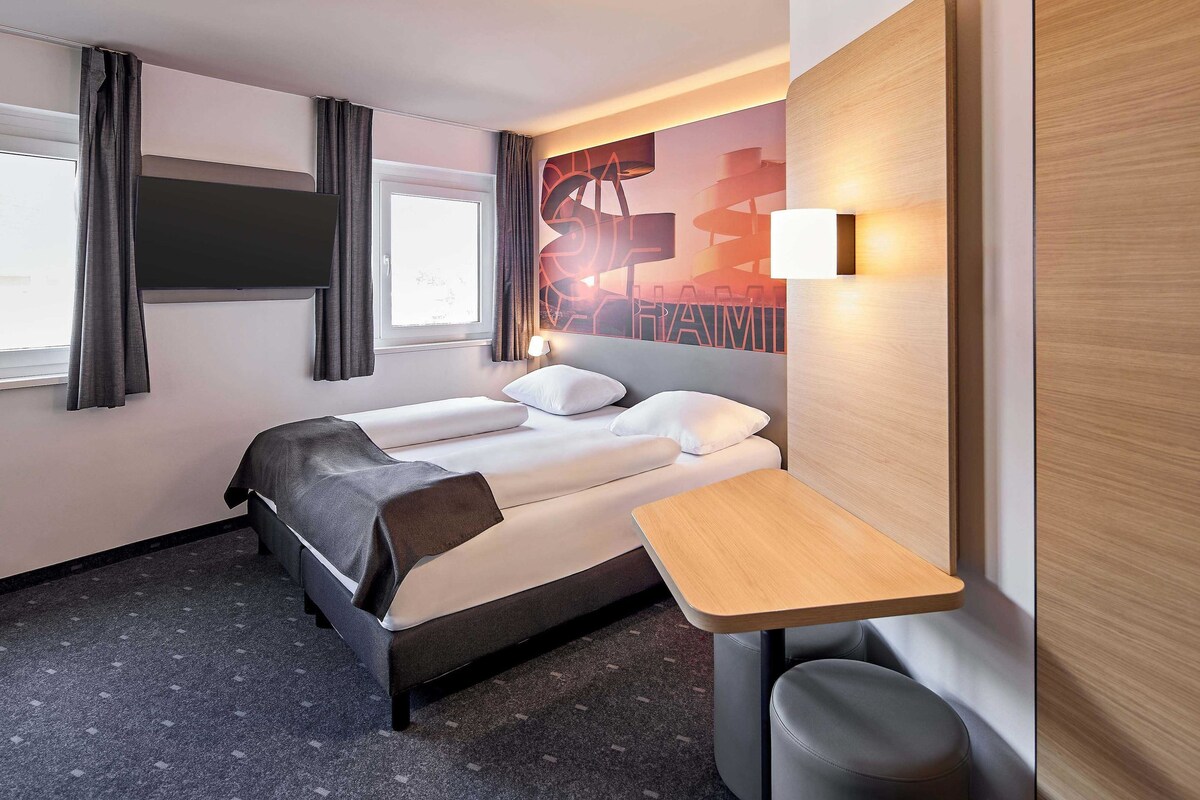 Una habitación de hotel con cama, escritorio y silla.