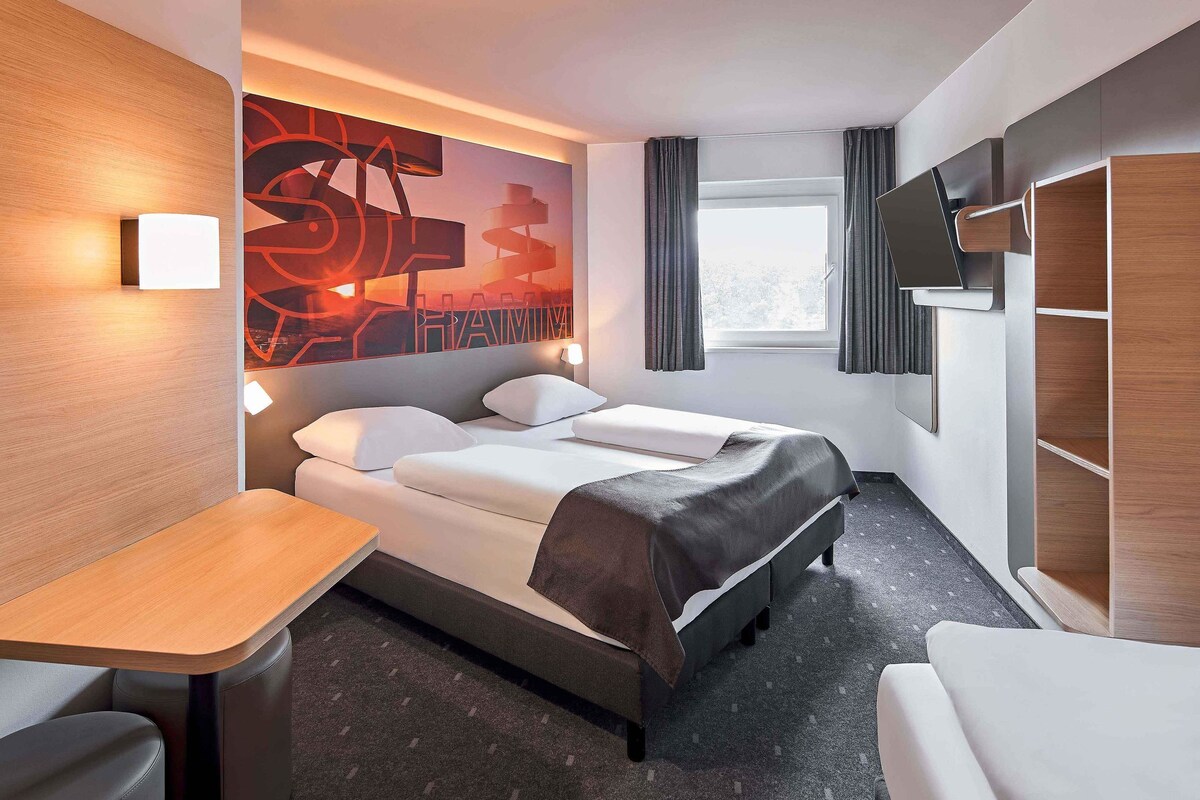 Una habitación de hotel moderna con cama, escritorio y televisor.