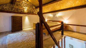 A rustic attic bedroom with a wooden bed, a dresser, and a stone wall. - Holiday home with balcony for 6 people (Bribir)