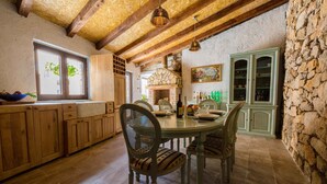 A rustic kitchen with wooden cabinets, a stone wall, and a dining table with chairs. - Holiday home with balcony for 6 people (Bribir)