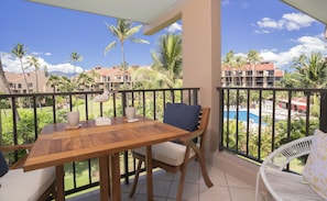 Enjoy a peaceful retreat on this balcony overlooking the pool and lush landscape with palm trees and distant mountains.