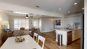 A spacious living area with a dining table, sofas, and a kitchen with a central island. - Private Heated Pool, Golf Cart Included and Close To Beach (Port Aransas)