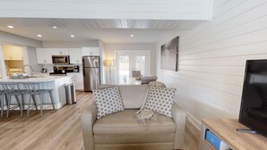 A modern kitchen with white cabinets, stainless steel appliances, and a dining area with a table and chairs. - Private Heated Pool, Golf Cart Included and Close To Beach (Port Aransas)