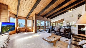 A spacious living area with a large TV, comfortable seating, and a view of the outdoors. - Tahoe's Most Sought After Lakeview -Cliff Hanger Home less than 1 Mile to Heavenly, Sleeps 10 (South Lake Tahoe)