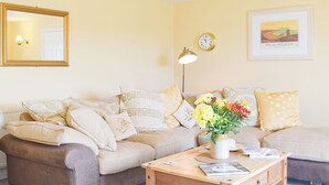 Un salon avec un canapé, une table basse, une lampe, une horloge et un tableau encadré au mur.