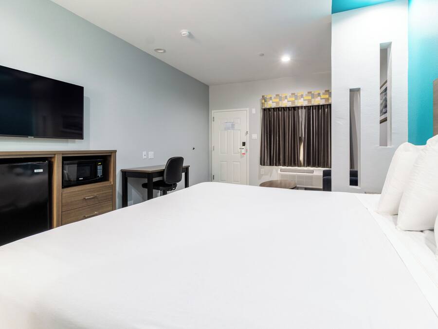 A hotel room with a bed, a TV, a microwave, a desk, and a chair.