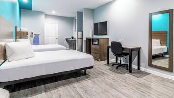 Hotelkamer met een bed, bureau, stoel, televisie, magnetron en kledingkast.