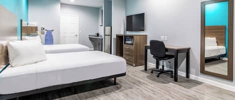 A hotel room with a bed, a desk, a chair, a TV, a microwave, and a wardrobe.