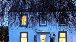 A two-story house with a front porch, a bench, and a wreath on the door. - Lower Canterbury House (Gattonside, near Melrose)