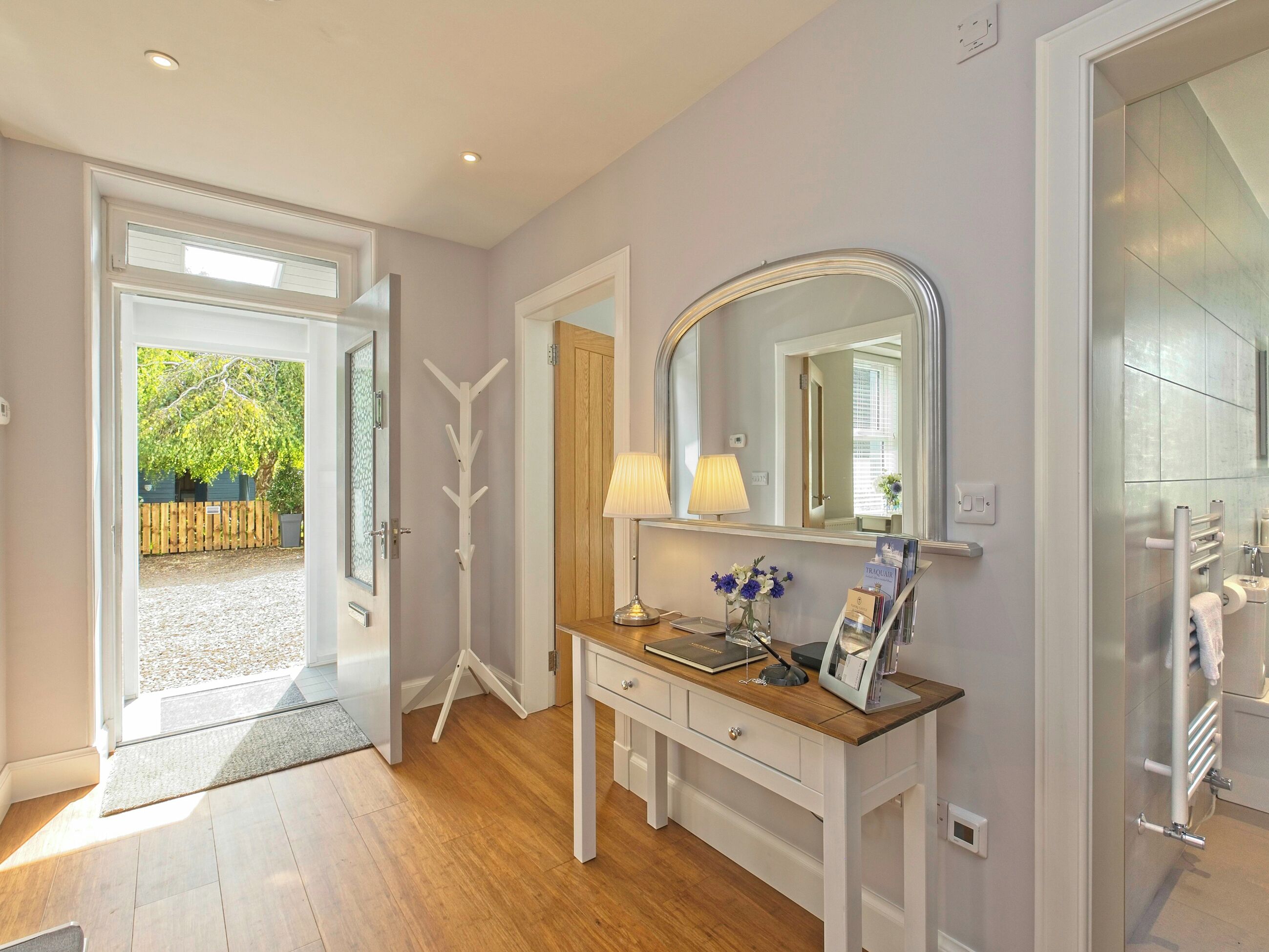 A modern bathroom with a large mirror, a vanity with a lamp, and a shower area.