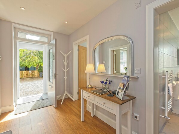 Un baño moderno con un espejo grande, un tocador con lámpara y una zona de ducha.