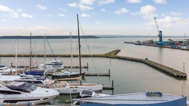 A marina with boats docked, a pier extending into the water, and a distant industrial area. - Sunnyside - Apartment Moments from Poole Quay (Poole)