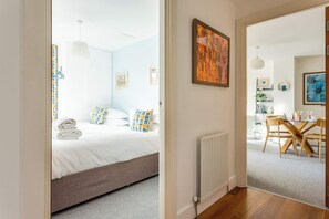 A bedroom with a bed, a radiator, and a dining area with a table and chairs.