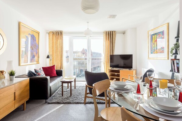 A modern living room with a sofa, dining table, and TV.