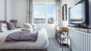 A hotel room with a bed, a desk, a television, and a window with curtains. - Sunnyside - Apartment Moments from Poole Quay (Poole)