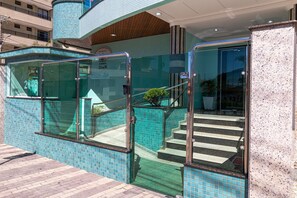 L’entrée d’un hôtel, avec des portes en verre, un mur recouvert de carreaux et un escalier menant à l’intérieur.