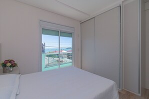 Een slaapkamer met een bed, een raam met uitzicht en een schuifdeur.