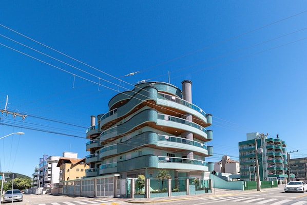 Un edificio de varios pisos con fachada curva, balcones y una chimenea visible.