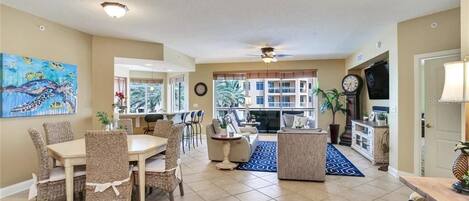 A spacious living room with a dining area, a fireplace, and a view of the outside.